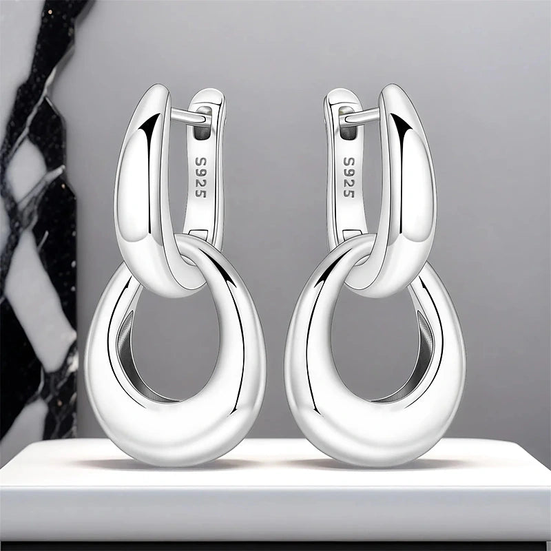 Boucles d'oreilles créoles Adrienne, la paire présentée sur un socle