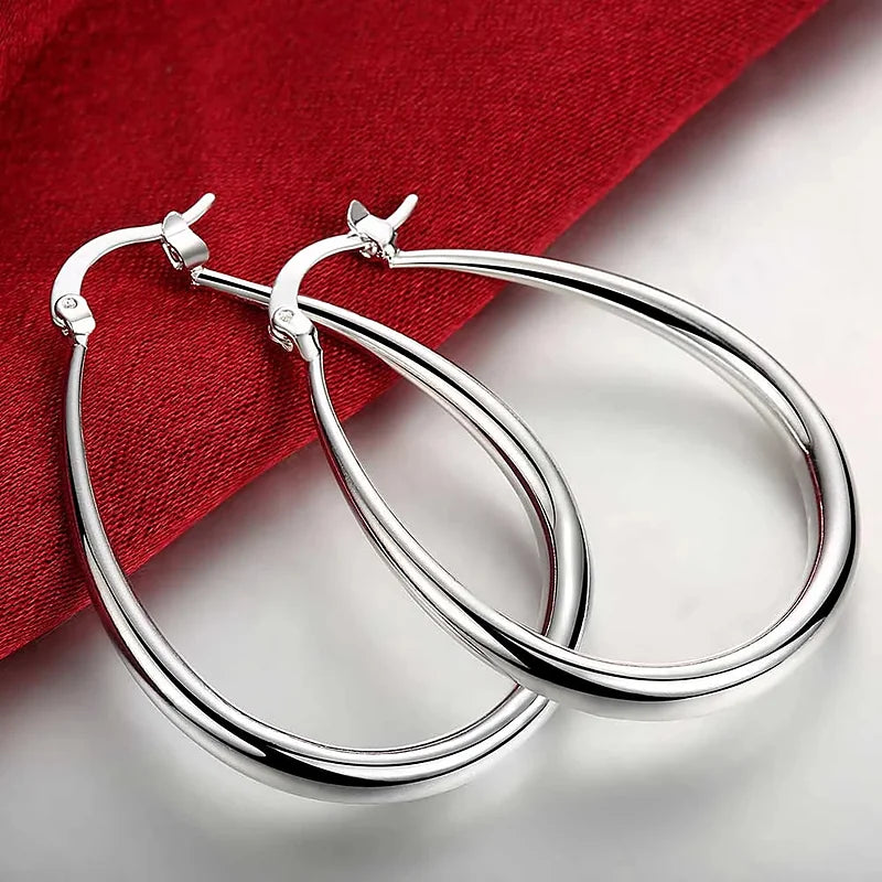 Boucles d'oreilles créoles Bérénice, la paire posée sur une soie rouge