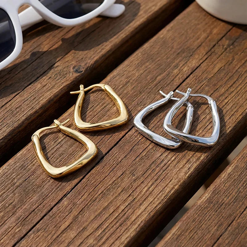 Boucles d'oreilles créoles Garance, les deux finitions posées sur du bois