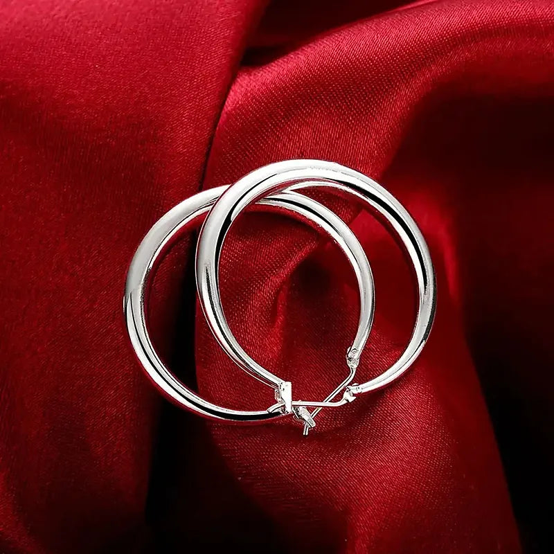 Boucles d'oreilles créoles Hortense, la paire posée sur une soie rouge