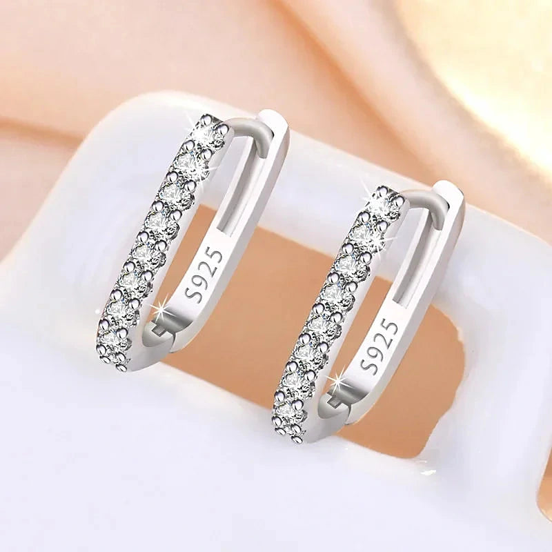 Boucles d'oreilles créoles Léonie, la paire argentée sur fond crème
