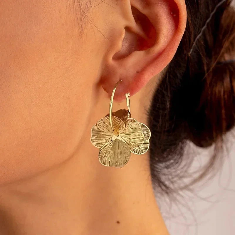 Boucles d'oreilles créoles Marguerite, portées dorées en gros plan sur l'oreille
