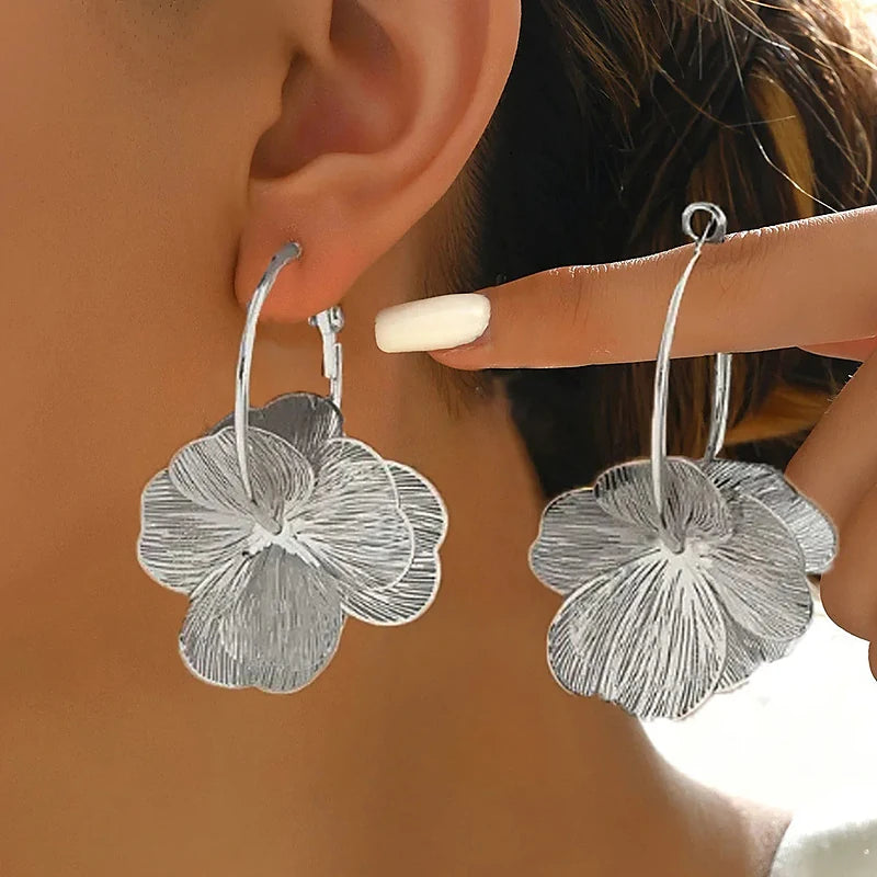 Boucles d'oreilles créoles Marguerite, la paire argentée tenue en main