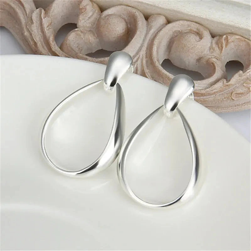 Boucles d'oreilles créoles Mathilde, la paire posée sur une pierre claire