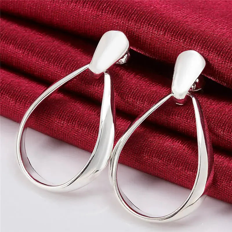 Boucles d'oreilles créoles Mathilde, la paire posée sur une soie rouge
