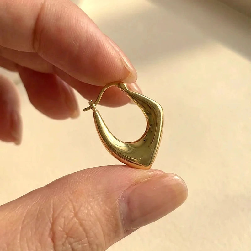 Boucles d'oreilles créoles Roxane, tenues entre les doigts pour montrer le volume