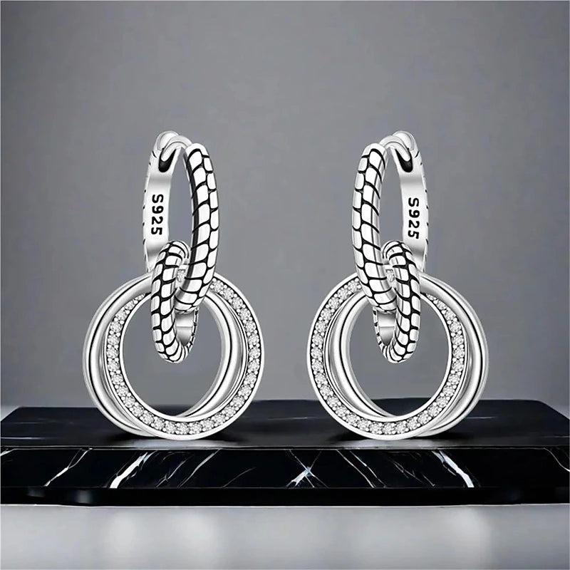 Boucles d'oreilles créoles Solène, la paire posée sur du marbre noir