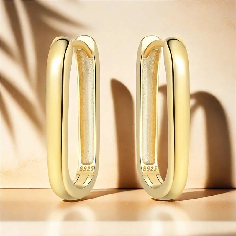 Boucles d'oreilles créoles Victoire, la paire dorée en lumière rasante