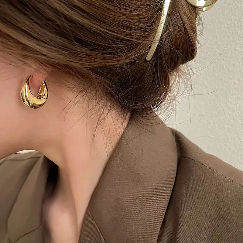 Boucles d'oreilles créoles Vivienne, portée dorée en gros plan sur l'oreille