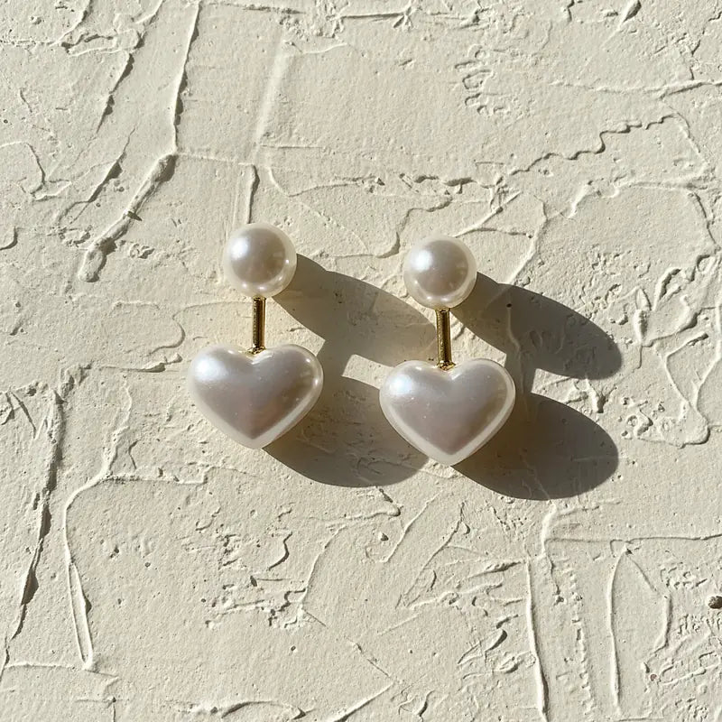 Boucles d'oreilles perles Amélie, posées sur une surface en plâtre crème
