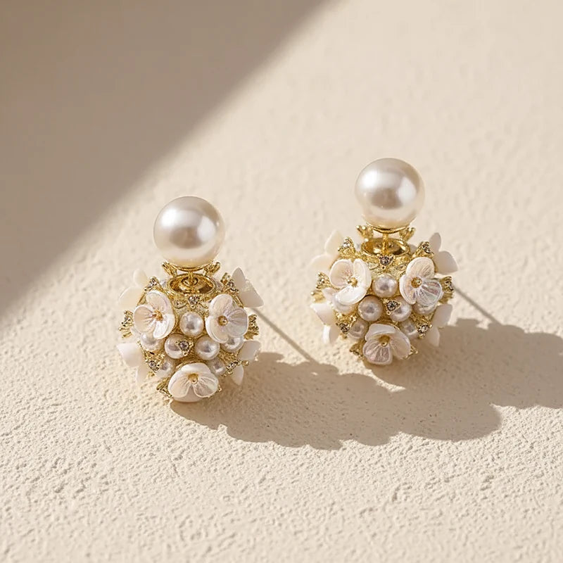 Boucles d'oreilles perles Camélia, posées sur une surface en plâtre crème