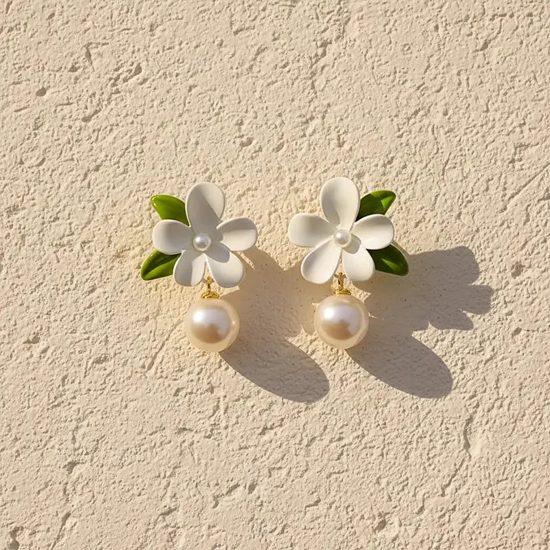 Boucles d'oreilles perles Capucine, posées sur une surface en plâtre crème