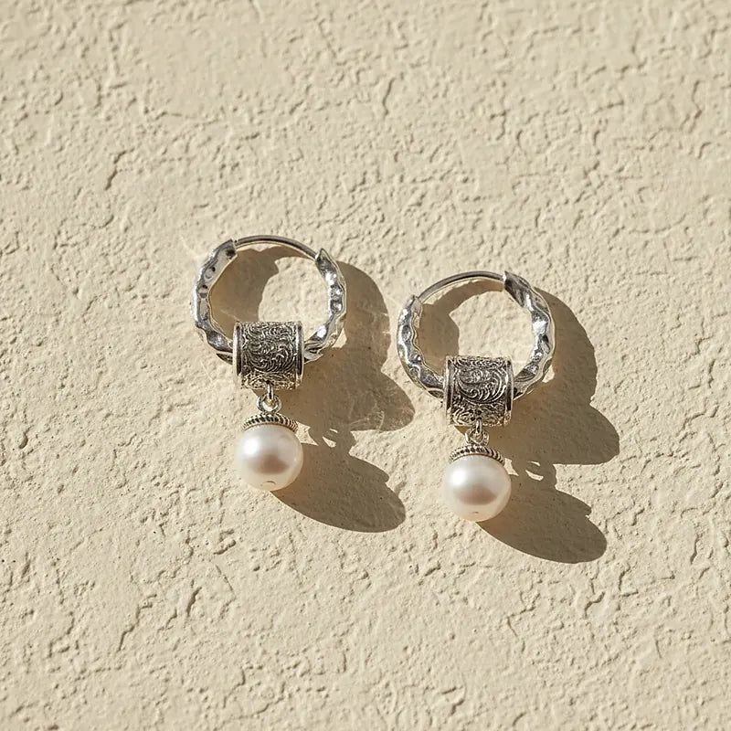Boucles d'oreilles perles Colette, posées sur une surface en plâtre crème