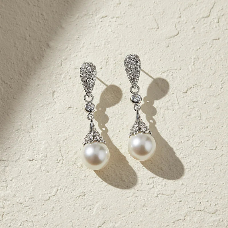 Boucles d'oreilles perles Eugénie, posées sur une surface en plâtre crème