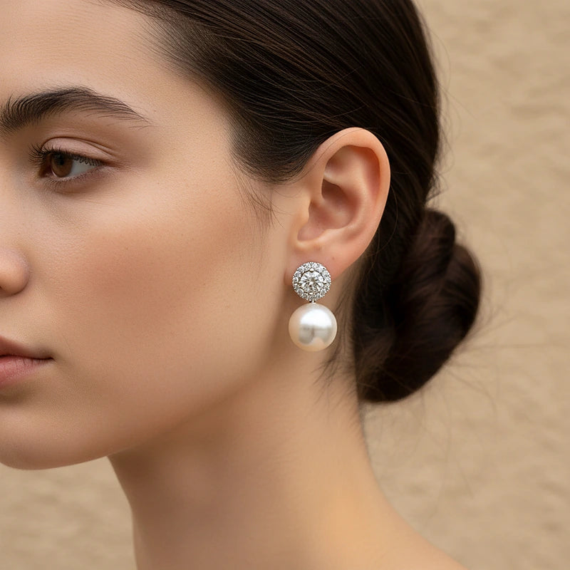 Boucles d'oreilles perles, halo de zircons argenté, portées en gros plan sur l'oreille