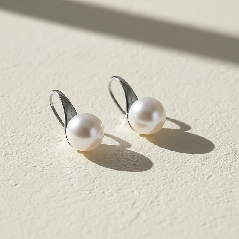 Boucles d'oreilles perles Lise, posées sur une surface en plâtre crème