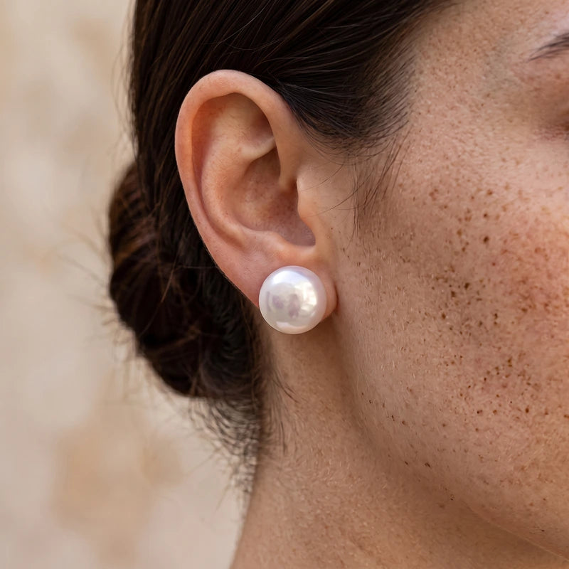 Boucles d'oreilles perles nacrées portées, gros plan macro sur le lobe