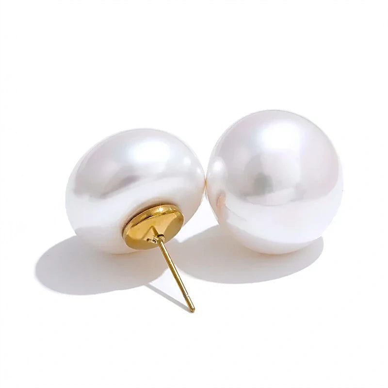 Boucles d'oreilles perles nacrées blanches sur tige en acier inoxydable doré, la paire sur fond blanc