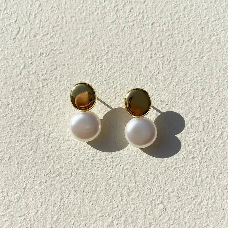 Boucles d'oreilles perles Noémie, posées sur une surface en plâtre crème