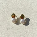 Boucles d'oreilles perles Noémie, posées sur une surface en plâtre crème