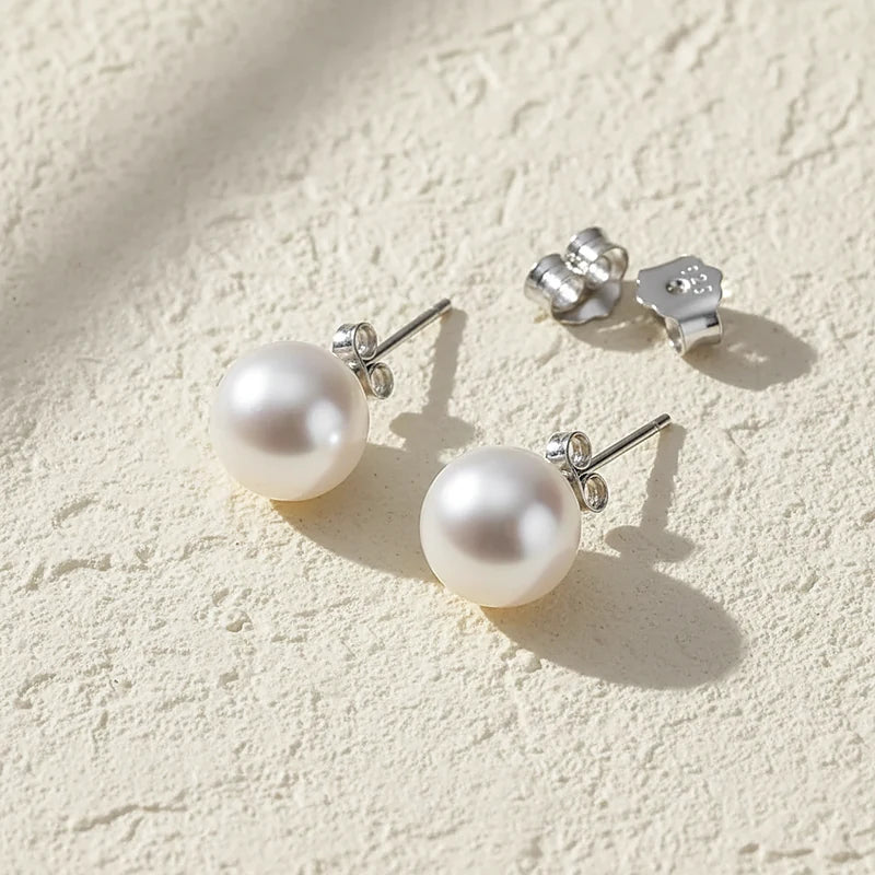 Boucles d'oreilles perles Simone, posées sur une surface en plâtre crème